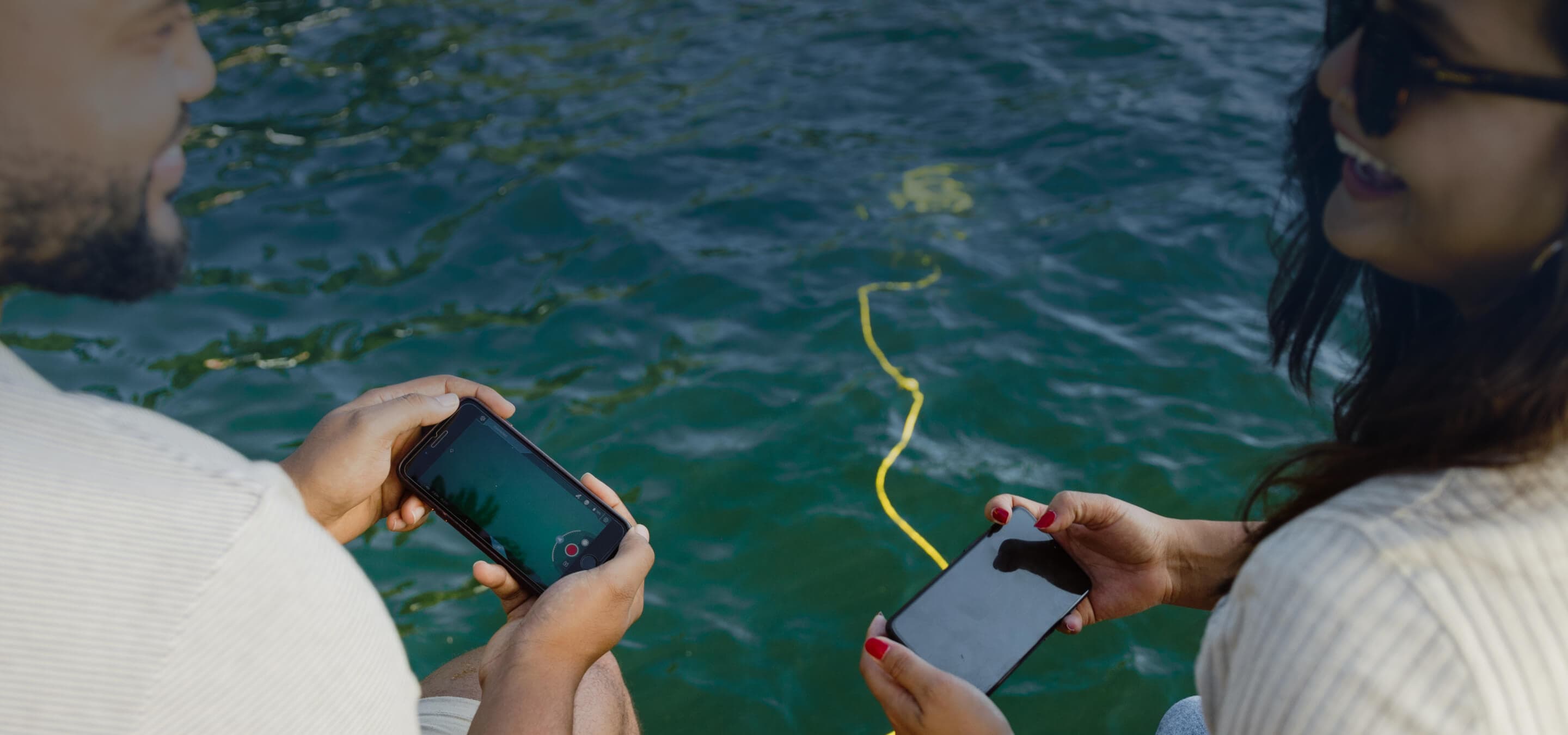 Dva lidé řídí CHASING DORY z telefonů u vody